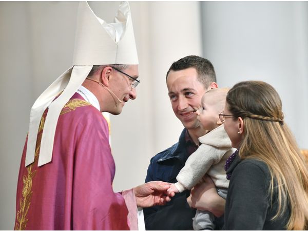Ellen und Tobias Büdel mit Theo begrüßen Bischof Gerber im Festgottesdienst - stellvertretend für alle Familien 